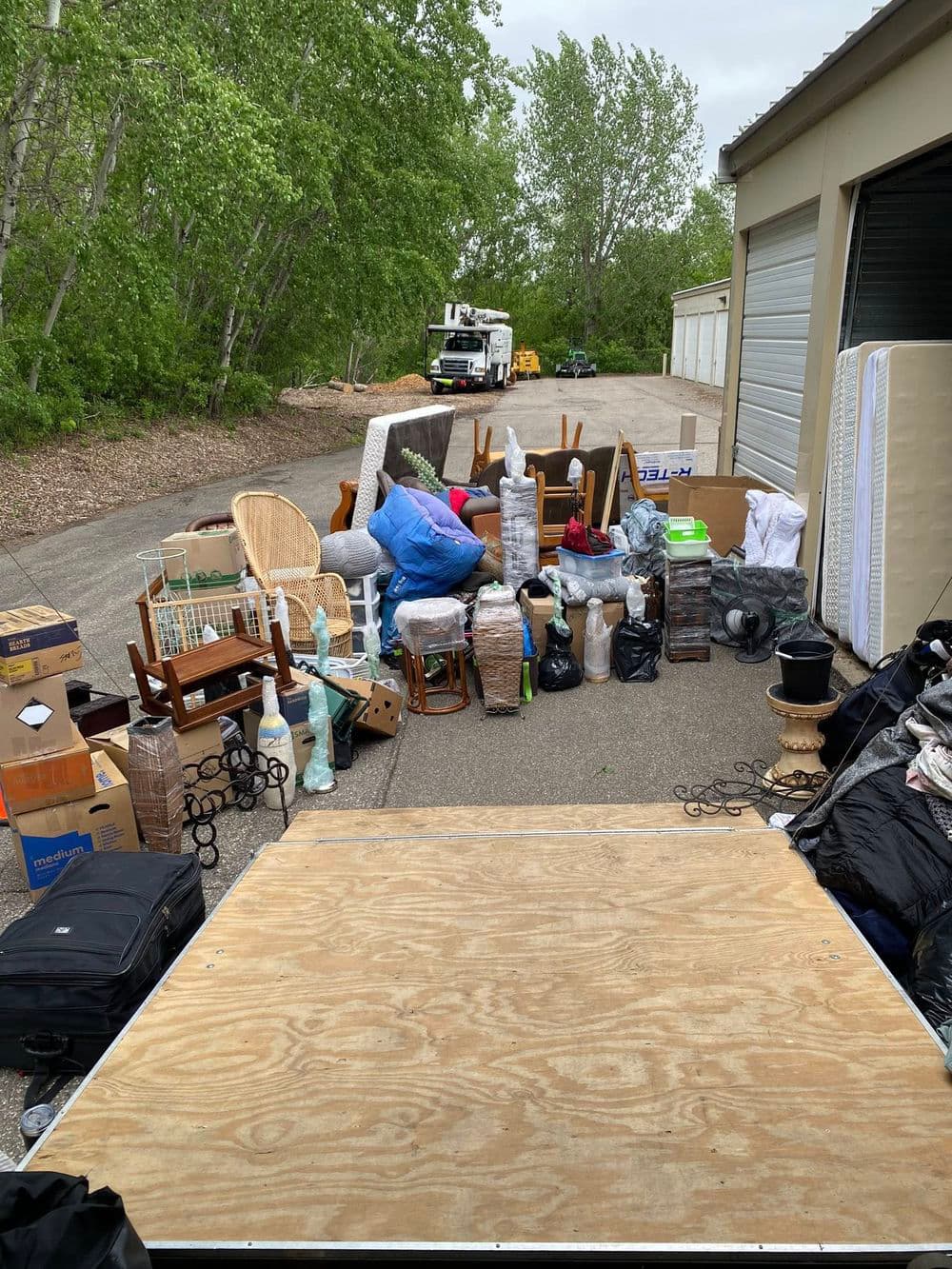 Outdoor scene of assorted furniture and boxes ready for moving or storage.