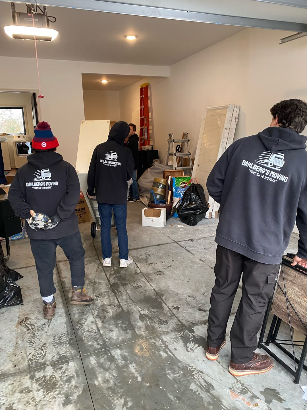 Moving crew in hoodies organizing a garage space with boxes and equipment.
